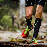 Runner using beige TapeGeeks kinesiology tape on knee for joint stability and muscle support during outdoor trail running.