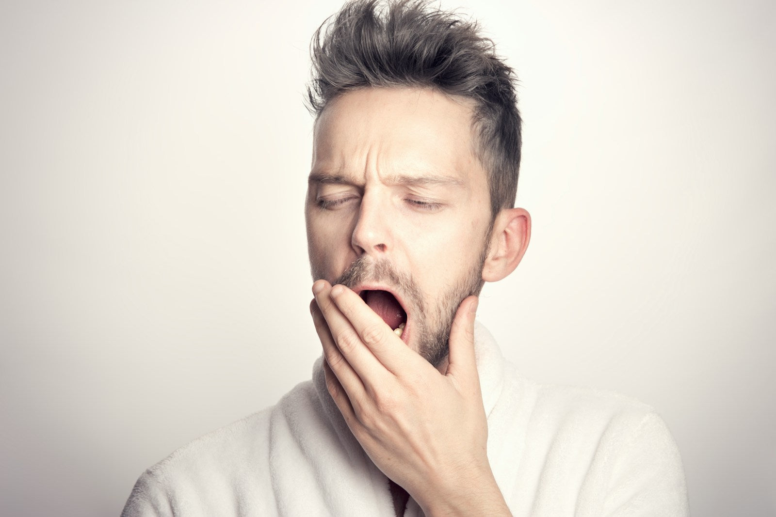 Tired man yawning in the morning with dry mouth after mouth breathing all night - a common sign of nighttime mouth breathing
