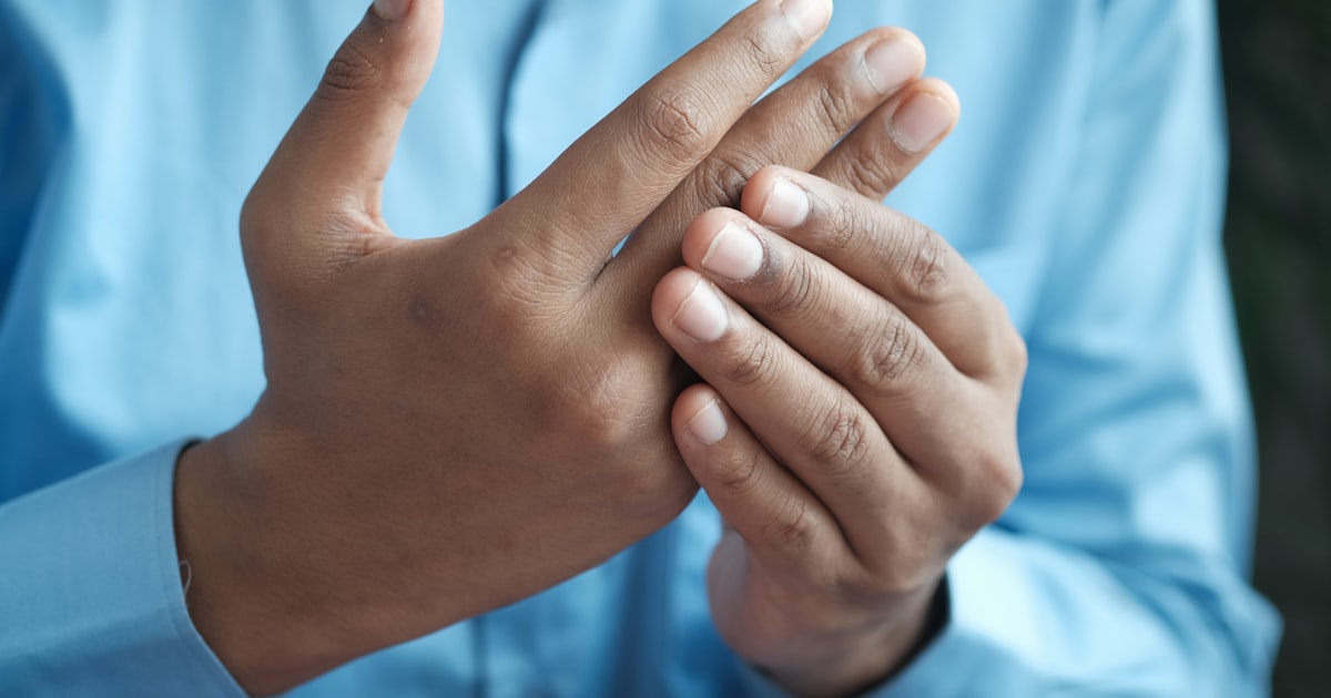 Person holding their wrist and hand, the kind of pain wrist taping is used for