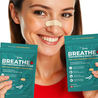woman smiling while wearing a beige tapegeeks nasal strip and holding breathe plus performance nasal strip packages