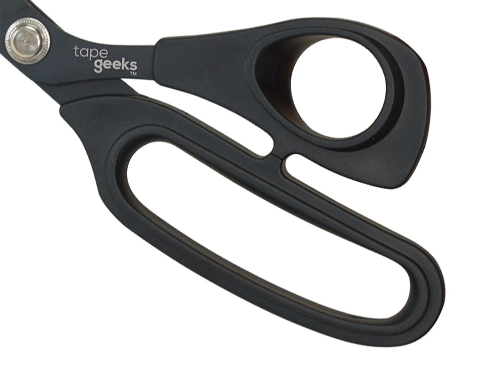 Close-up of the ergonomic, rubber-coated handles on TapeGeeks kinesiology scissors, showing the non-slip grip that improves comfort and control during cutting.

